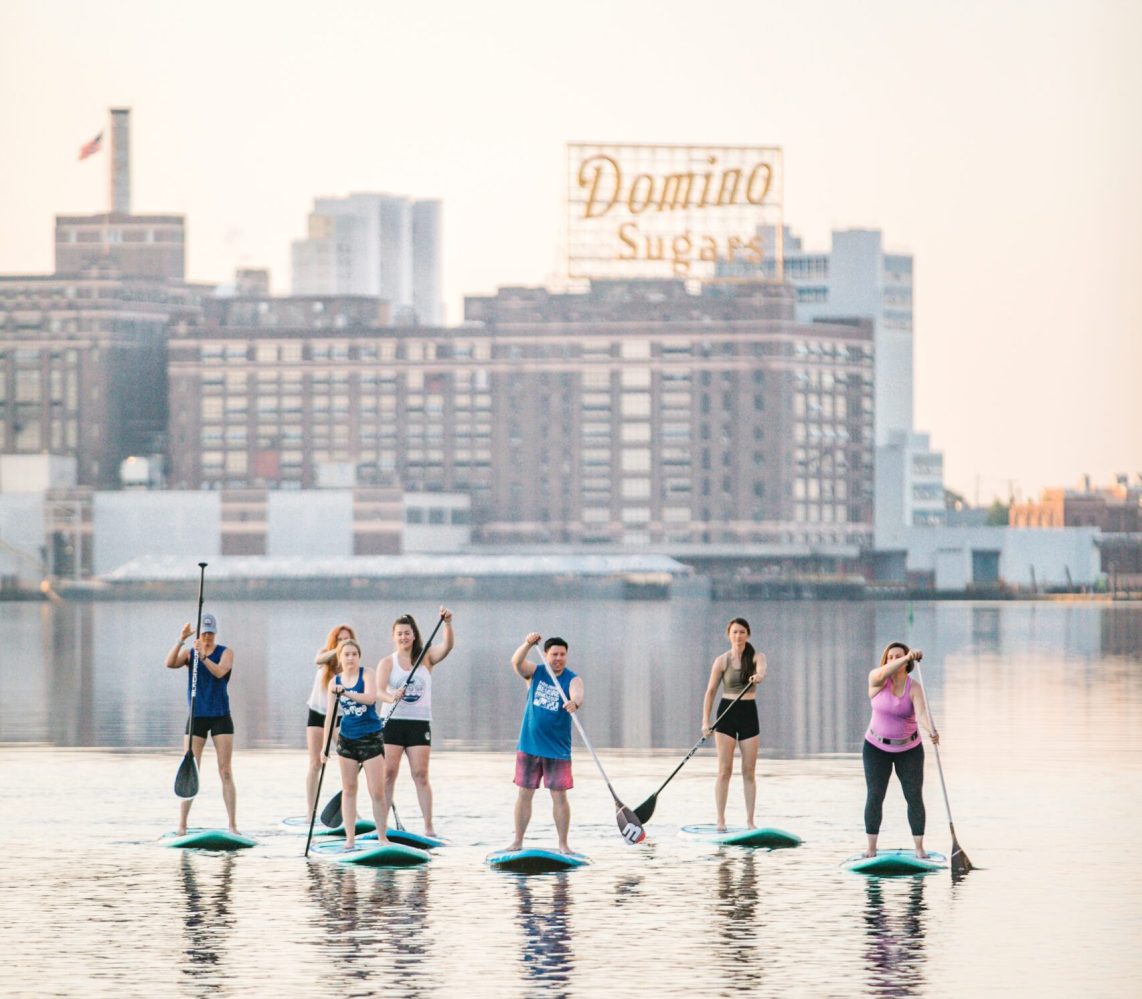 A group of people stand up paddleboarding in Baltimore's Inner Harbor. 